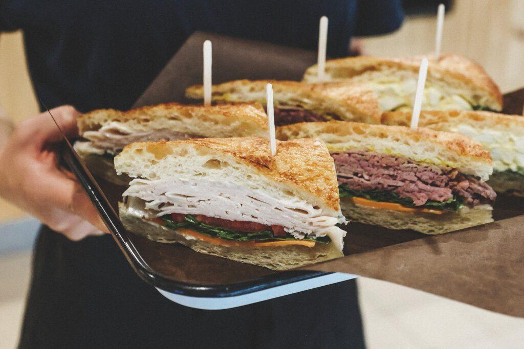 An employee delivering a tray of sandwiches for a customer's Catering Ottawa order